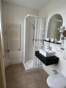 La salle de bains est pourvue d'une douche et d'un lavabo. dans l'établissement Hotel Poseidon, à Kühlungsborn