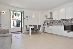 a kitchen with white cabinets and a table with chairs at Sirena Apartment in Minori