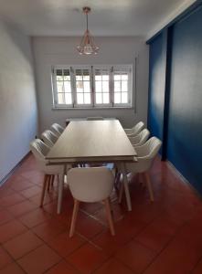 a dining room with a wooden table and white chairs at Parfum de la Mer in Sines