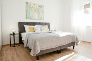 a white bedroom with a large bed with yellow pillows at Apartment Mila in Zadar