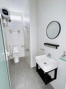 Baño blanco con lavabo y espejo en EURO HOUSE, en Da Lat