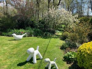 a garden with three white statues in the grass at Le moulin de la Castellerie in Moon-sur-Elle