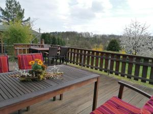 une terrasse en bois avec une table et des fleurs. dans l'établissement Ferienhaus Chiara, Südharz, Harztor, à Ilfeld