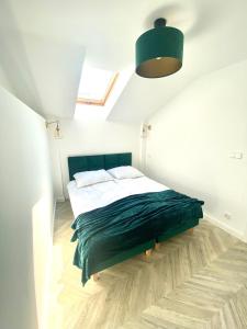 a bedroom with a bed with a green blanket at Apartament Sanok-z widokiem na rynek i tarasem in Sanok