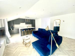 a living room with a blue couch and a kitchen at Apartament Sanok-z widokiem na rynek i tarasem in Sanok