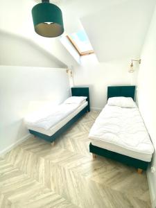 2 Betten in einem Zimmer mit Holzböden in der Unterkunft Apartament Sanok-z widokiem na rynek i tarasem in Sanok