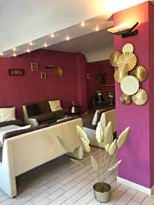 een woonkamer met paarse muren en banken en een plant bij Hotel del Falco in Cervia