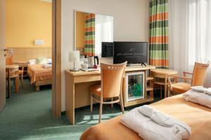 a hotel room with two beds and a desk with a television at Spa Resort Sanssouci in Karlovy Vary