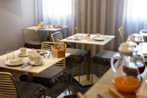 - une salle à manger avec deux tables, des chaises, des tasses et des assiettes dans l'établissement Ingrid Rooms Tropea, à Tropea