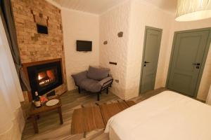 HERAKLES HOTEL في تشيشمي: غرفة نوم بسرير ومدفأة وكرسي