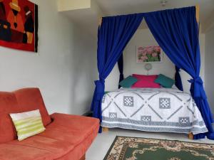 a bedroom with a bed with blue curtains and a chair at Hosteria Rose Cottage in Otavalo