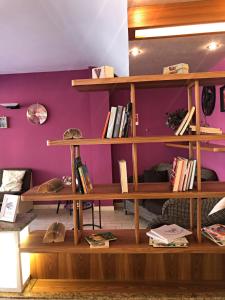 une étagère en bois avec des livres dans une pièce dotée d'un mur violet dans l'établissement Hotel del Falco, à Cervia