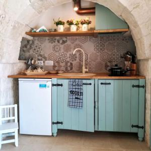 La cuisine est équipée de placards verts et d'un réfrigérateur blanc. dans l'établissement Villa Fransisca, à Alberobello