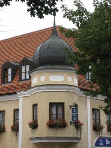 ein Gebäude mit einem gewölbten Dach mit Blumen darauf in der Unterkunft Altstadthotel Schex in Altötting