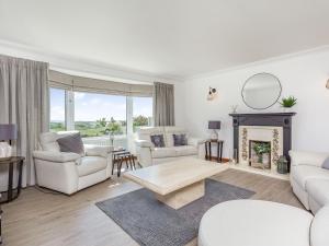 a living room with white furniture and a fireplace at Craigievar in Cruden Bay