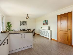 a kitchen with white cabinets and a wooden door at Craigievar in Cruden Bay