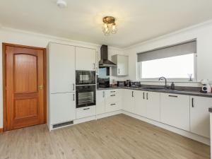 an empty kitchen with white cabinets and a window at Craigievar in Cruden Bay