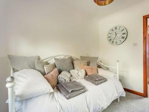 a white bed with pillows and a clock on the wall at Craigievar in Cruden Bay