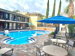 a pool with tables and chairs and an umbrella at Days Inn by Wyndham Pensacola - Historic Downtown in Pensacola