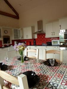 una cocina con una mesa con un jarrón de flores. en The Barn at Freemans Farm en Alveston