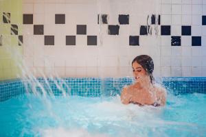a woman in a swimming pool with water coming out at Gran Hotel Don Manuel in Cáceres