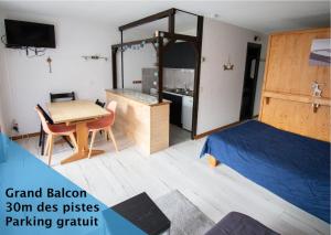 a bedroom with a bed and a table and a kitchen at Relai S11 Grand et lumineux studio avec coin montagne 4-6 pers, WIFI, 30m des pistes, grand balcon, DRAPS NON COMPRIS in Saint-Jean-d'Aulps