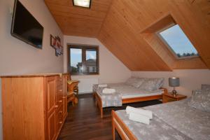 a attic room with a bed and a tv at Agroturystyka Nad Stawem in Górno