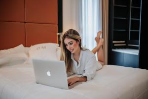 a woman laying on a bed with a laptop at Gran Hotel Don Manuel in Cáceres