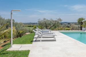 - une rangée de chaises longues à côté de la piscine dans l'établissement Villa Peter, à Ostuni