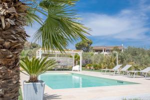a swimming pool with a palm tree next to a house at Villa Peter in Ostuni