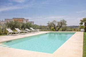 a swimming pool with lounge chairs next to a building at Villa Peter in Ostuni