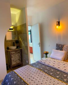 a bedroom with two beds and a bathroom with a sink at Gîte les 2 cèdres in Cardet