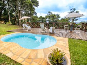 a swimming pool on a deck with chairs and an umbrella at Pousada VillaSerrana in Monte Verde