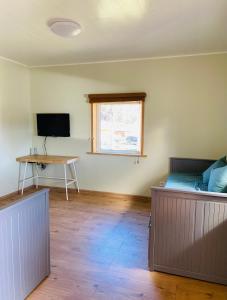 Schlafzimmer mit einem Bett, einem Schreibtisch und einem TV in der Unterkunft Lūšių vėjas in Palūšė