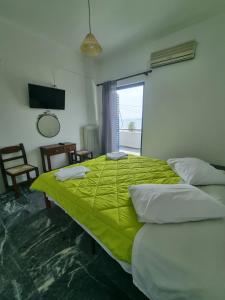 a bedroom with a bed with a green blanket on it at To Kyma in Amarinthos