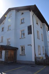a white building with a wooden door in a parking lot at FeWo's und Apartment's Blaues Haus in Davos