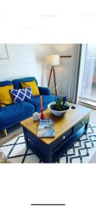a living room with a blue couch and a coffee table at Charming, cosy waterside retreat in Gimingham, North Norfolk in Gimingham