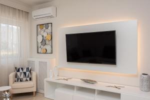 a white living room with a television on a wall at G&J Deluxe Apt in Zakynthos Town
