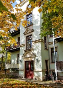 a white house with a red door and trees at Stilvolle 1-Raum-Wohnung zentral, ruhig gelegen in Dresden