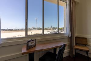 uma secretária em frente a uma janela com vista para o aeroporto em Logis Hôtel Rêve de Sable em Royan