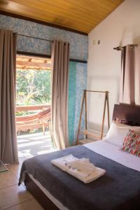 um quarto com uma cama e uma grande janela em Vila Flores Pousada em Serra do Cipó