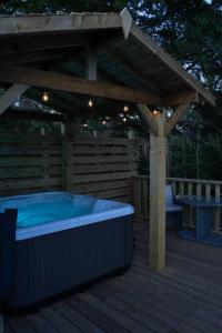 a hot tub on a wooden deck with a pergola at Luxurious Cottage with hot tub, Lake District in Duddon