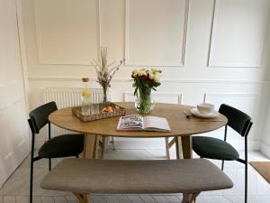 een eettafel met stoelen en een vaas met bloemen bij Stylish & Chic Central Apartment with Hot Tub in Perth