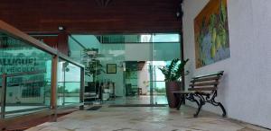 a bench in a lobby with glass doors and a plant at Araça Flat Natal Prime - Beira Mar in Natal