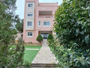 a pink apartment building with a green yard at Treasure star B&b in Salamina