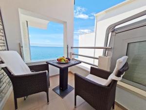 balcón con mesa, sillas y vistas al océano en Hotel Sunce, en Podstrana