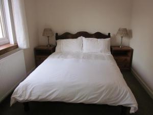 ein Bett mit weißer Bettwäsche und Kissen in einem Schlafzimmer in der Unterkunft Easter Bowhouse Farm Cottage in Linlithgow