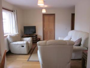 a living room with white furniture and a flat screen tv at Easter Bowhouse Farm Cottage in Linlithgow