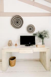 a living room with a tv on a white table at Hôtel Restaurant Les Arnelles in Saintes-Maries-de-la-Mer