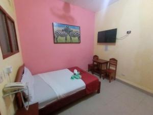 um quarto com uma parede rosa com uma cama e uma cadeira em Hospedaje California Inn em Iquitos